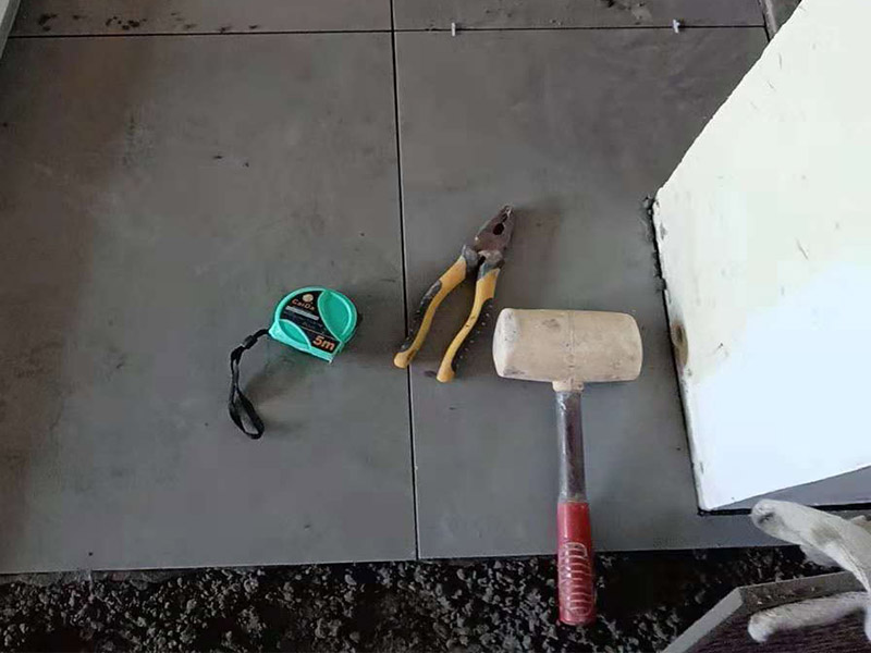 客廳地磚鋪貼：鋪貼的工具包括橡膠錘和粘結(jié)劑。在進(jìn)行施工之前先把所需要的這些材料都整理好放在一旁備用；基層的處理工作對(duì)瓷磚的平整度有很大的影響，對(duì)于基層要做好清潔工作，還有找平工作。放樣：在進(jìn)行瓷磚的鋪貼工作之前還事先找好垂直線，這樣可以在鋪貼的時(shí)候找到瓷磚的水平線，讓瓷磚鋪貼的更加的平整。粘結(jié)劑加水?dāng)嚢杈鶆颍o置10分鐘之后就可以使用。將瓷磚表面的浮灰清除，再在瓷磚背面均勻的涂抹上粘結(jié)劑，按照預(yù)鋪的順序?qū)⒋纱u鋪貼在地面上，最后用橡膠錘輕輕拍打至服帖齊整。
