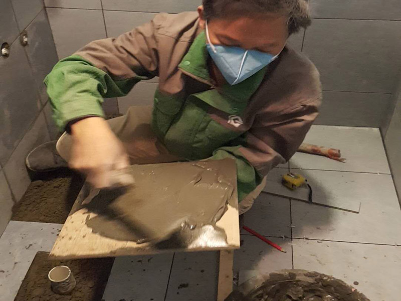 廁所貼地磚：
1、基層處理：把沾在基層上的浮漿、落地灰等用暫子或鋼絲刷清理掉，再用掃帚將浮土清掃干凈。
2、找標高：根據(jù)水平標準線和設計厚度，在四周墻、柱上彈出面層的上平標高控制線。
3、排磚：將房間依照磚的尺寸留縫大小，排出磚的放置位置，并在基層地面彈出十字控制線和分格線。
4、鋪設結合層砂漿：鋪設前應將基底濕潤，并在基底上刷一道素水泥漿或界面結合劑，隨刷隨鋪設攪拌均勻的干硬性水泥砂漿。
5、鋪磚：將磚放置在于拌料上，用橡皮錘找平，之后將磚拿起，在干拌料上澆適量素水泥漿，同時在磚背面涂厚度約lnm的素水泥膏，再將磚放置在找過平的干拌料上，用橡皮錘按標高控制線和方正控制線坐平坐正。
6、鋪磚時應先在房間中間按照十字線鋪設十字控制磚，之后按照十字控制磚向四周鋪設，并隨時用2m靠尺和水平尺檢查平整度。大面積鋪貼時應分段、分部位鋪貼。
7、養(yǎng)護：當磚面層鋪貼完24h內(nèi)應開始澆水養(yǎng)護，養(yǎng)護時間不得小于7d。