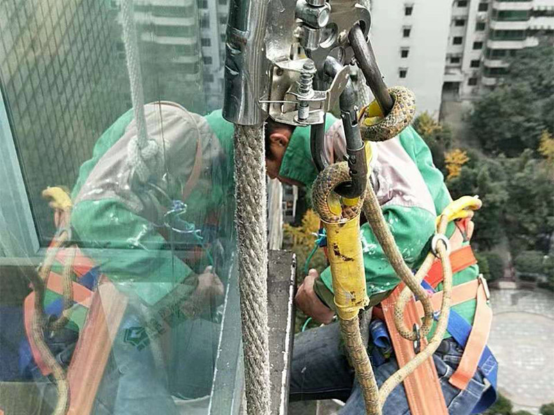 高空外墻施工：1、目前外墻粉刷主要有兩種方式：吊板方式和吊籃方式。 2、吊板方式是用吊繩、吊板將人吊到工作位置進行清洗。一般的大樓都可以用這種方式進行清洗，但是這種方式的操作必須使安全措施到位，否則危險性很大，造成傷亡事故的都是因安全措施不到位造成的。 3、墻面破損、裂縫、不平整等部位在底涂前用外墻耐水膩子修補平整。每次批刮膩子的厚度控制在2mm之內，批刮膩子的總厚度不超過5mm。膩子應堅實牢固，不得粉化、起皮或干裂。 4、干后，要用砂紙打磨平整，再用濕布將膩子上的浮灰抹去，并盡快涂漆，以免再次落灰。