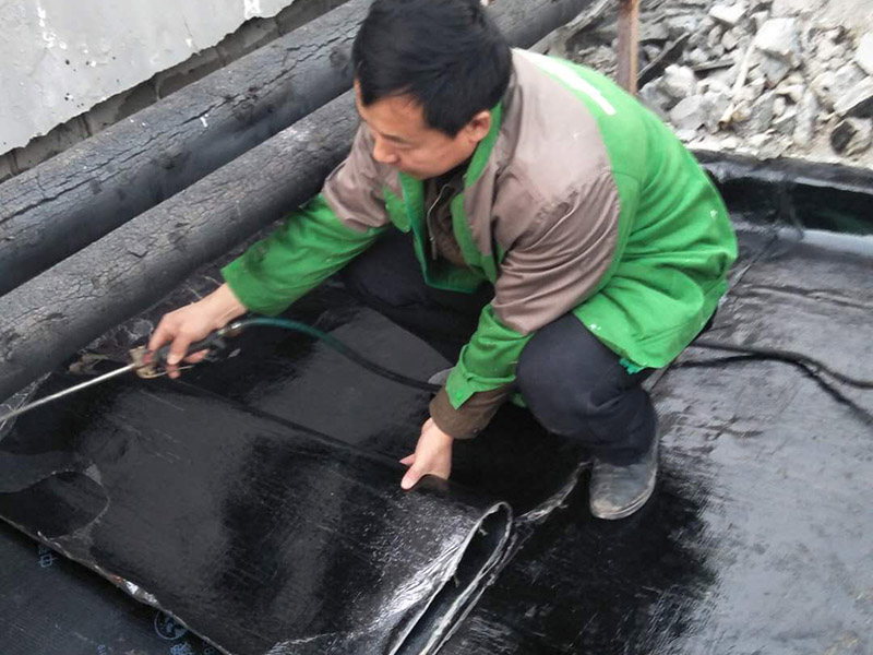 屋頂貼防水卷材：首先做好基礎(chǔ)準(zhǔn)備工作，清理基層，施工前將驗(yàn)收合格的基層表面塵土、建筑雜物清理干凈。接著涂刷基層處理劑，高聚物改性瀝青卷材施工，攪拌均勻后，用長(zhǎng)把滾刷均勻涂刷于基層表面上，常溫經(jīng)過4h后，開始鋪貼卷材。熱熔封邊，將卷材搭接處用噴槍加熱，趁熱使二者粘結(jié)牢固，以邊緣擠出瀝青為度；末端收頭用密封膏嵌填嚴(yán)密。防水層蓄水試驗(yàn)，卷材防水層完工后，確認(rèn)做法符合設(shè)計(jì)要求，將所有雨水口堵住，然后灌水，水面應(yīng)高出屋面最高點(diǎn)20㎜，24h后進(jìn)行認(rèn)真觀察，尤其是管根、風(fēng)道根，不滲不漏為合格，否則應(yīng)進(jìn)行返工。