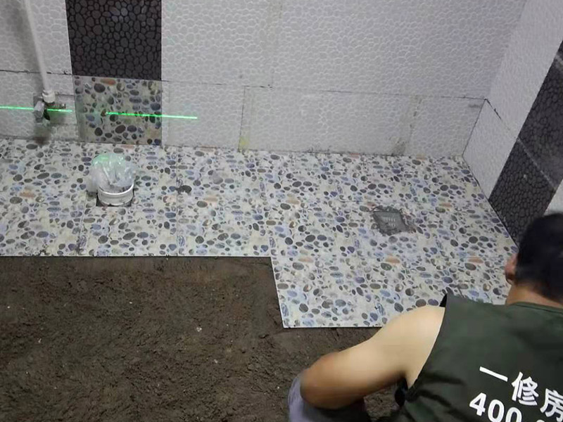 衛生間地面花磚鋪貼:找平，就是在鋪仿古磚前，對鋪貼物表面進行處理，如地面、內墻面、外墻面等，消除表面附著的污物，并灑水進行滋潤，然后用水泥沙混合找平，通常使用灰鏟在表面不停的涂抹使水泥地面保持大致水平，一定要等到水泥沙混合物完全干爽后再行鋪貼。用一段較長的細線，根據確定的鋪貼方式，在線上涂上顏色或白灰，然后在找平的地面上畫出仿古磚的位置及磚縫的參考線。 將亞光磚置入清水中浸泡，使瓷磚充分吸收水分，以不冒出氣泡為準，防止干燥瓷磚在裝修完成后再次吸水而導致磚體變形。取出浸泡好的瓷磚，抹干水漬，在找平層上噴灑足夠的水，然后在磚背面均勻抹上水泥沙漿，沙漿厚度5~6cm為宜，鋪貼大規格亞光磚時適當加厚；隨即將磚貼上，用木錘輕輕拍牢平整，避免空鼓，并隨時用直尺找平。