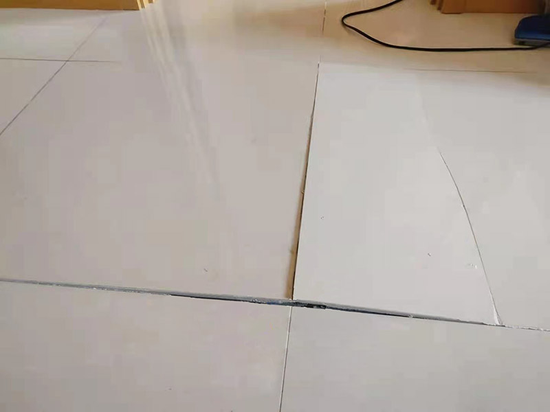 客廳地磚起翹修復：將油灰刀的邊緣滑入松散的瓷磚與其旁邊的瓷磚之間的接縫中。撬起瓷磚并將其移除。用金屬刮刀或小的撬桿的平坦邊緣刮掉基材和瓷磚背面的稀釋劑或瓷磚粘合劑。用相同的工具刮擦周圍空間的舊水泥漿。用清水沖洗除去翹起的瓷磚，然后用濕海綿擦拭，使其干凈。將砂漿抹在缺口邊緣上，然后將稀釋水泥砂漿抹在瓷磚的背面，將瓷磚鋪回原位。如果難以將瓷磚平整，則將瓷磚墊片插入接縫或修補物與包圍它的瓷磚之間的接縫或接縫中。刮掉多余的漿液，并讓該區域靜置約10分鐘。用水蘸軟海綿，然后輕輕擦拭修復區域。瓷磚上出現一層干粉后，請用干抹布擦拭。